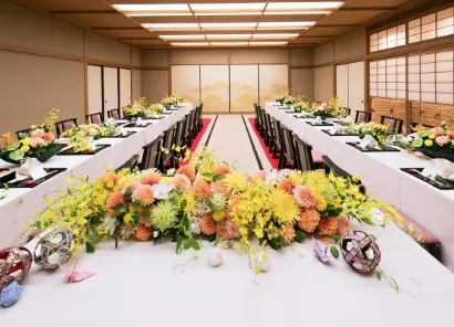 手前に花が飾られた新郎新婦のテーブルがあり、左右から奥に招待客のテーブルが並べられている