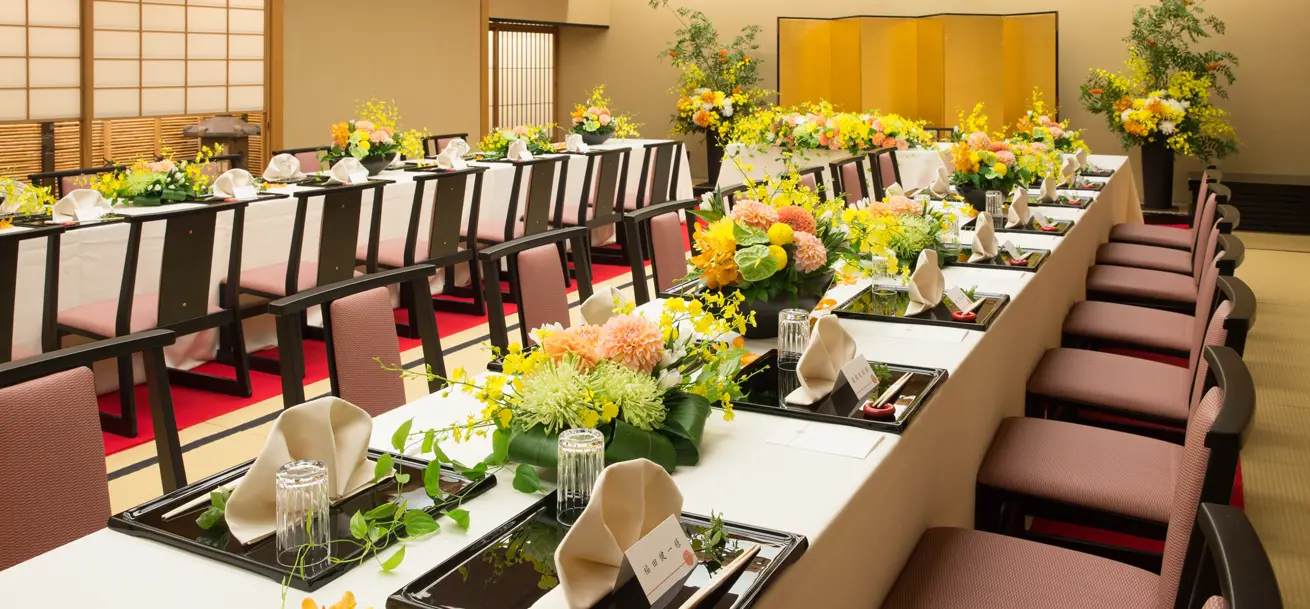 奥に金屏風が立ち、テーブルの上には花と皿が並べられている