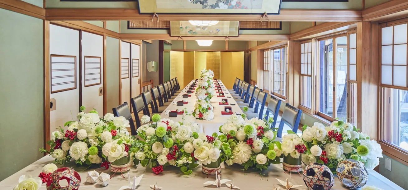 テーブルの上に花束が飾られ、奥に金屏風がある和室の会場