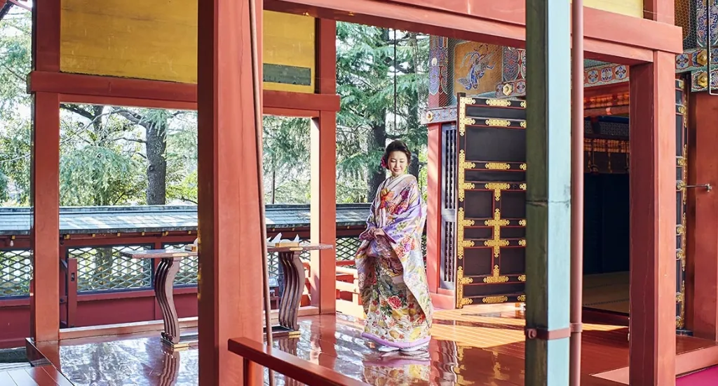 赤い柱や床の浅草神社境内を歩く着物姿の女性